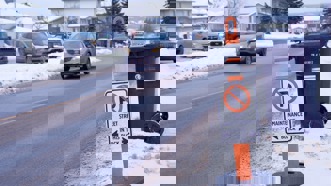 Temporary no parking sign on the street with a vehicle driving by